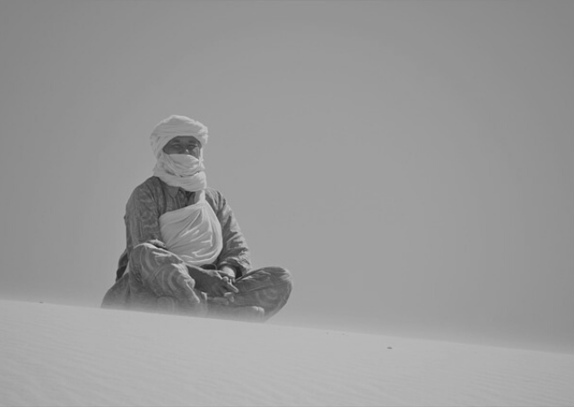 Hombre sentado en una duna en un desierto en Argelia